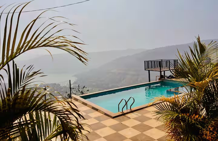 Pool through palm leaves at Paramount's Vinayaka holiday home Panchgani